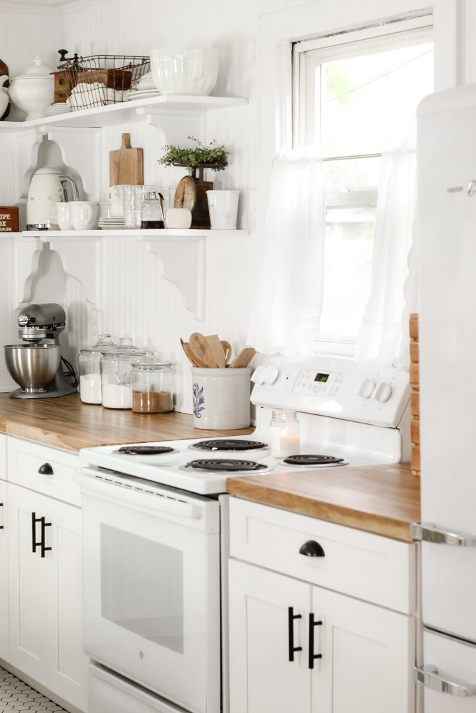 white cottage kitchen with cafe curtains butcher block countertops and open shelves