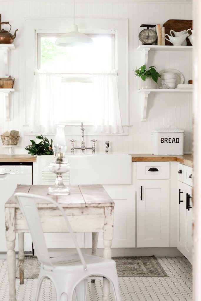 mosaic tile floor with vintage farmhouse table white shaker style cabinets farmhouse sink and open shelving