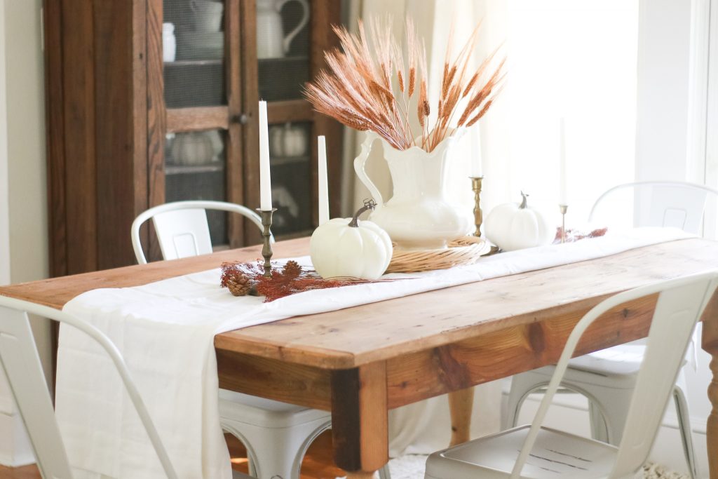 fall tablescape with antique vase with dried wheat and brass candlesticks