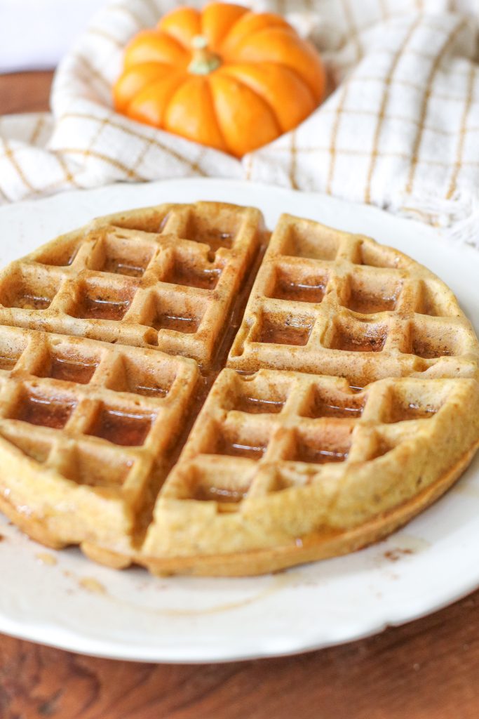 pumpkin sourdough waffle on white plate with syrup