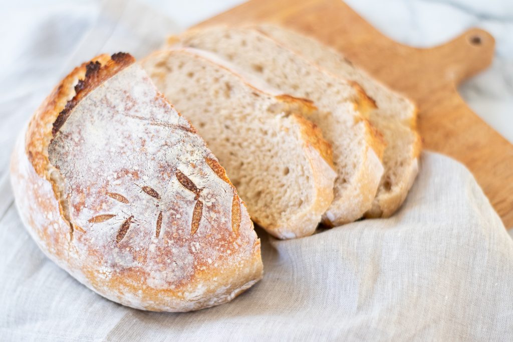 sliced artisan bread on cutting board with wheat scoring