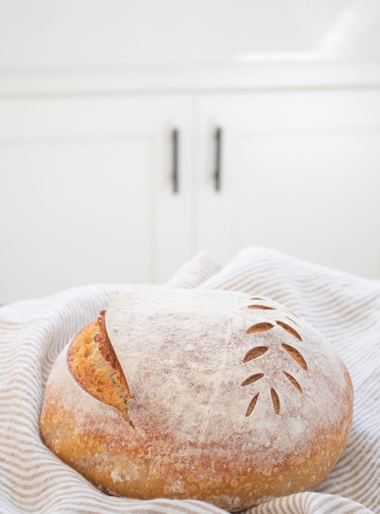 artisan sourdough bread cooling on striped linen tea towell