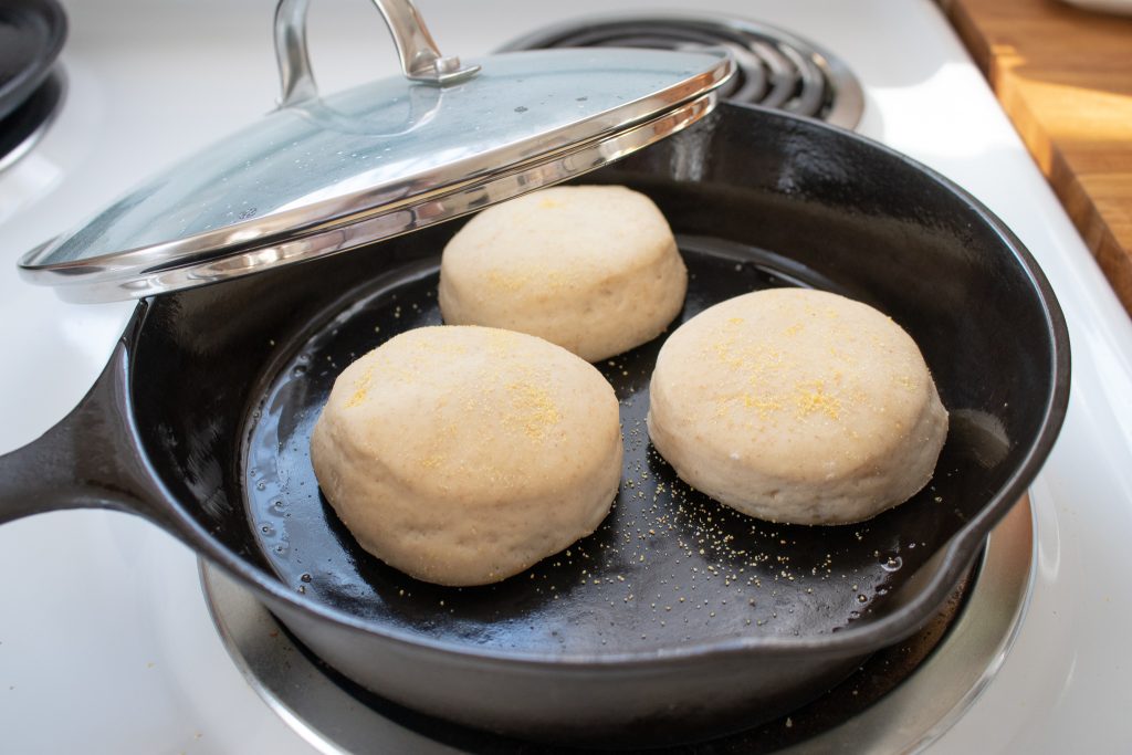 English muffins cooking on cast iron skillet