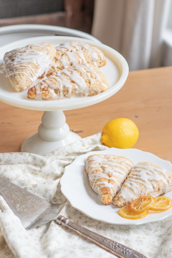 Sourdough scones on cake stand and sitting on white plate with fresh lemon and floral fabric