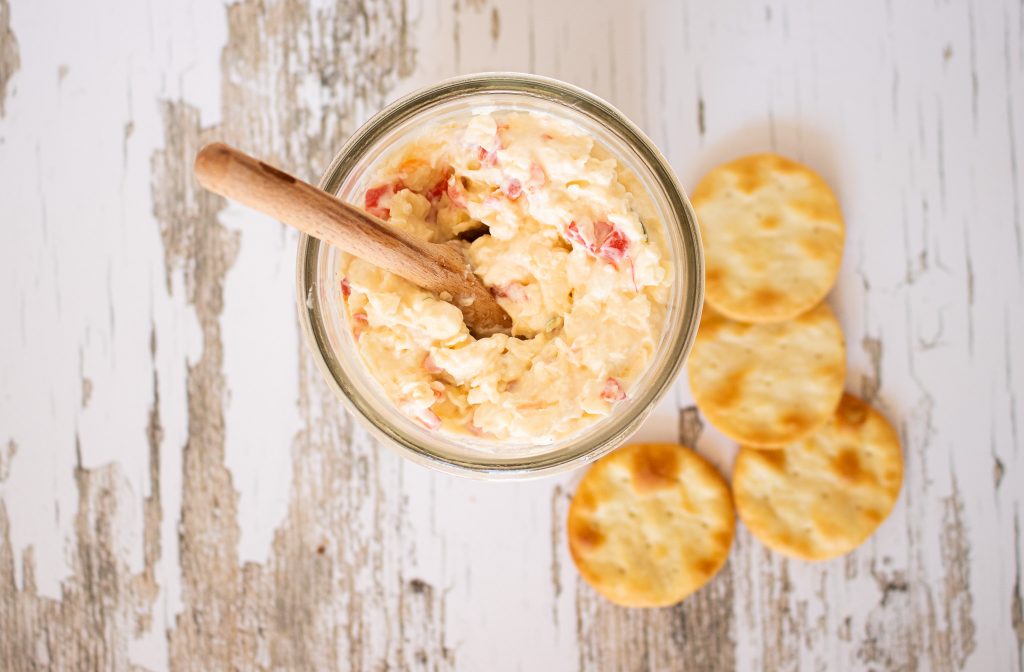 smoked Smoked Gouda and Goat Pimento Cheese spread in mason jar with spoon and pita crackers