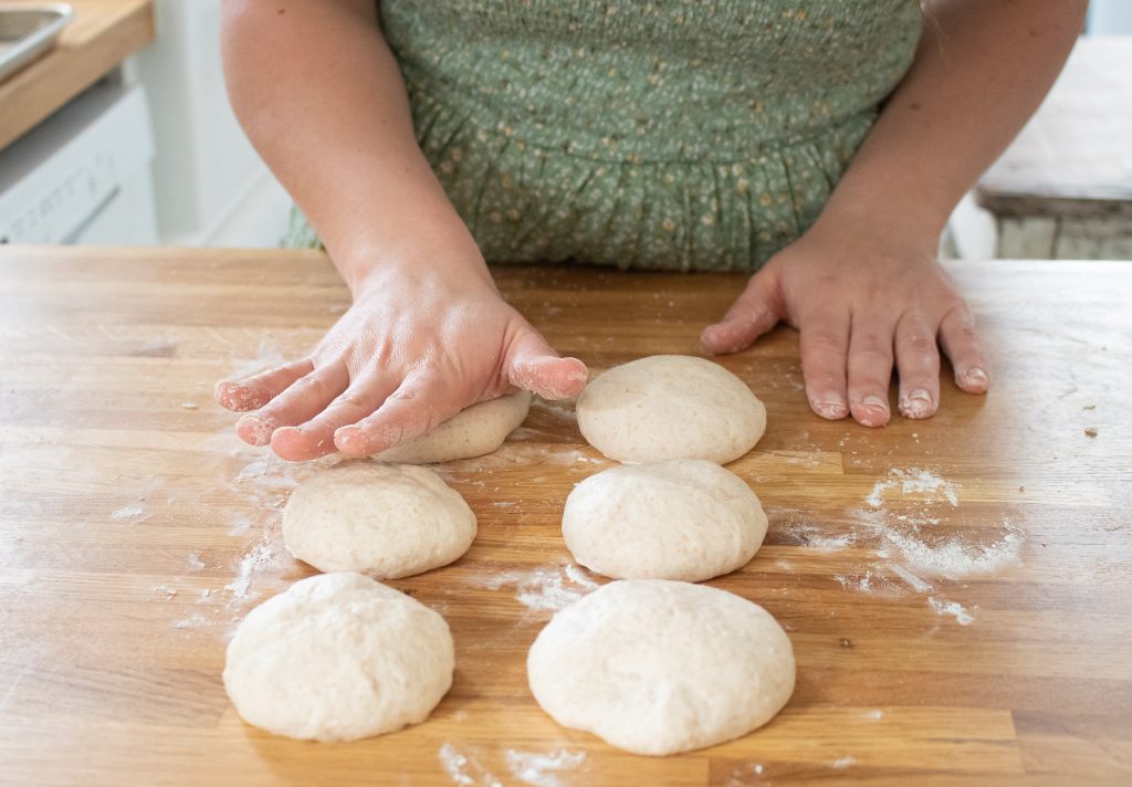 lady pressing bagel dough with palms of hand