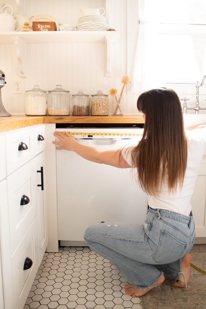 lady measuring opening for covering a dishwasher