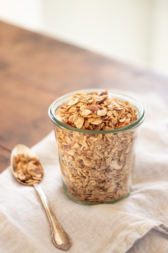 golden crunchy maple granola with slivered almonds In glass jar on old wooden table