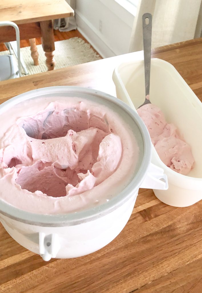 thick creamy pink strawberry raw milk ice cream being scooped from kitchen aid ice cream maker