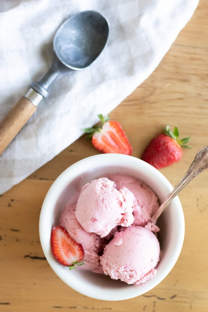 creamy scoops of raw milk strawberry ice cream in white bowl