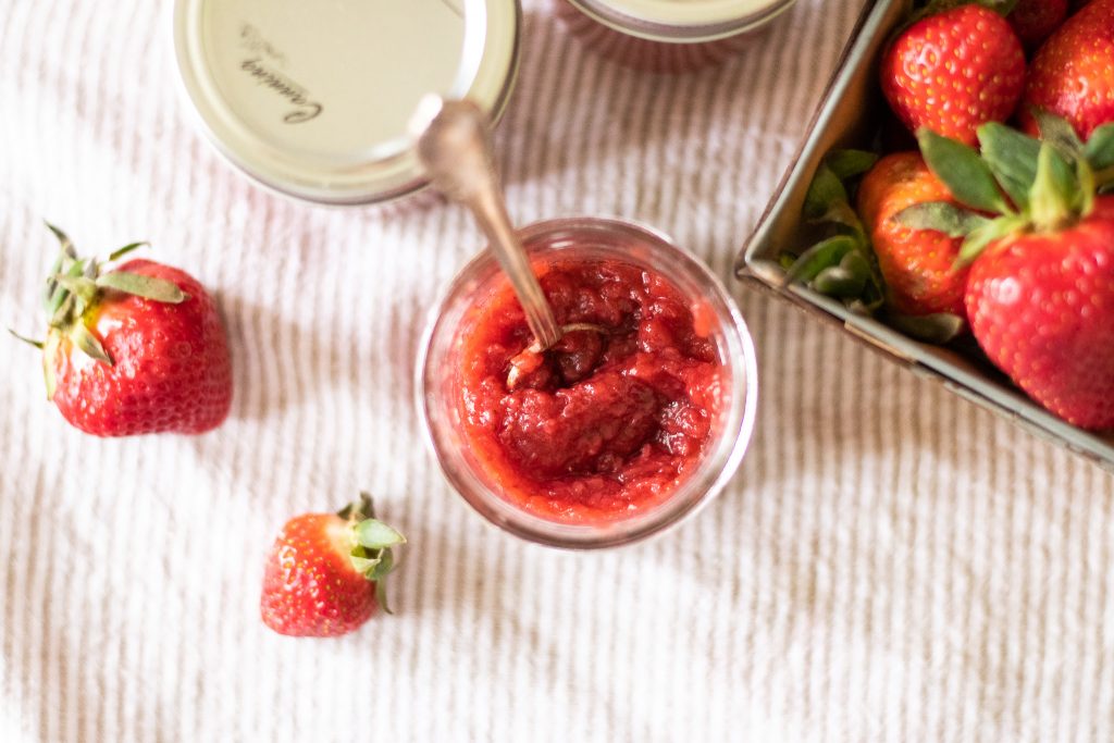 strawberry jam on striped tea towels beside fresh strawberries 