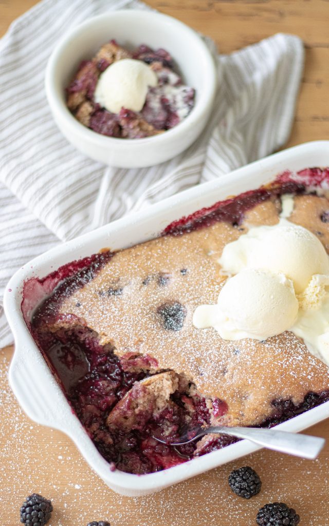 simple Old fashioned blackberry cobbler served in white baking dish with serving scooped out