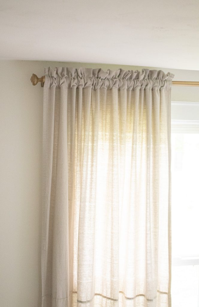 Gathered top drop cloth curtain hanging from brass curtain rod