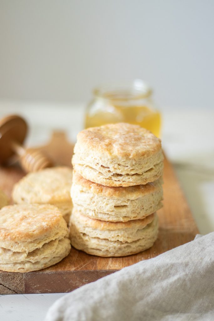 flaky sourdough buttermilk biscuits stacked together on cutting board